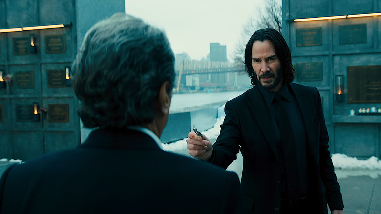 John Wick handing something to Winston