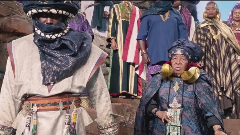 A crowd in ceremonial garb stands on a mountainside