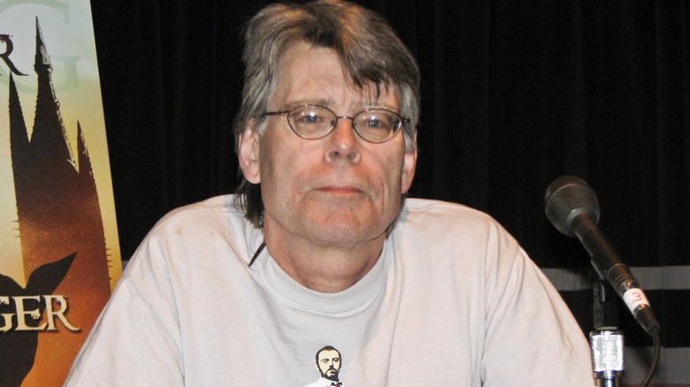 Stephen King sits in front of a microphone on a discussion panel