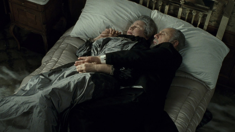 Old couple holds each other in sinking bed