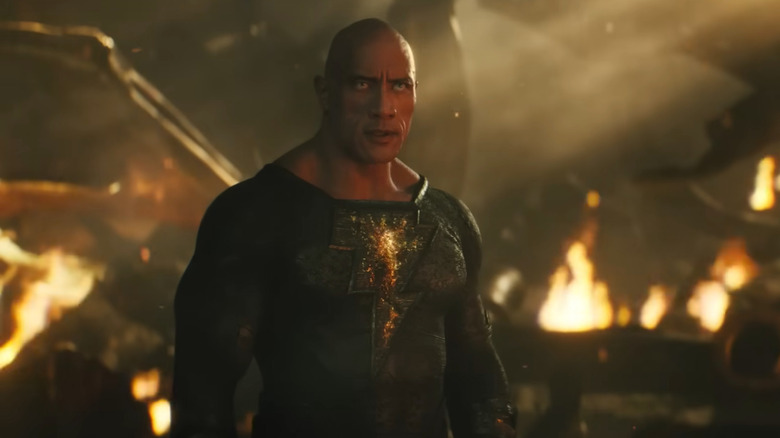 Black Adam standing in front of flaming ruins