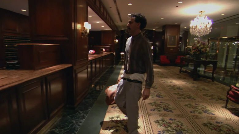 Borat walking through hotel lobby with pants low