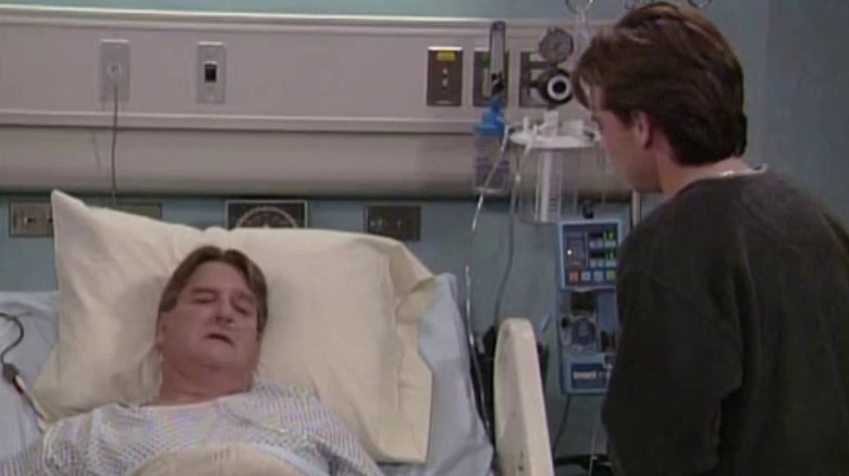 Shawn stands over hospital bed