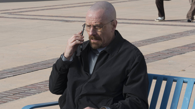 Walter White using a phone on bench