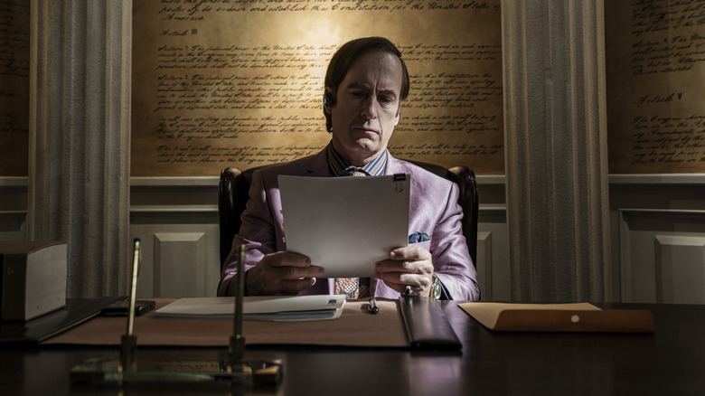 Bob Odenkirk reads behind a desk 