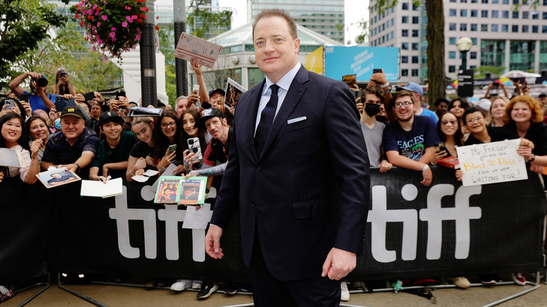 Brendan Fraser with fans standing behind him