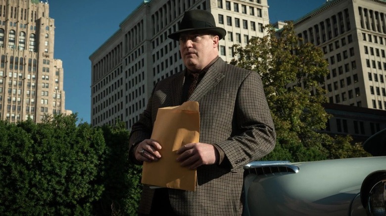 Man holds envelope next to car