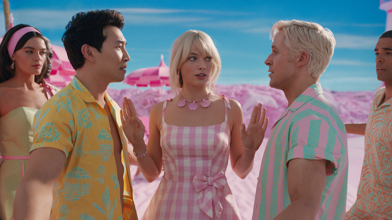 Barbie, Ken, Barbie, Ken, and Ken talking on the beach