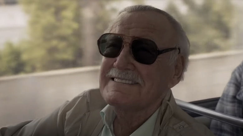 Stan Lee on bus smiling with sunglasses