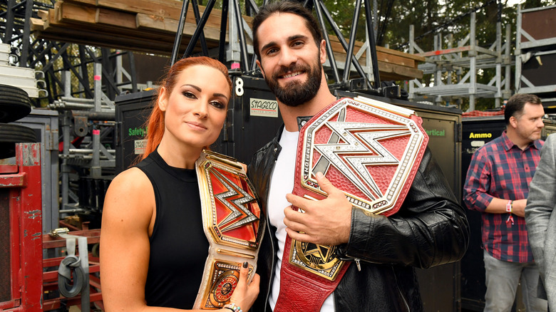 Seth Rollins posing with Becky Lynch holding WWE belts