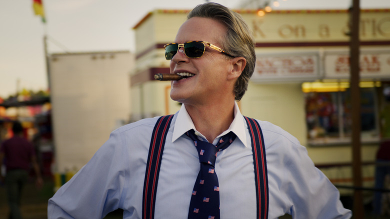 Cary Elwes as Larry smiling and smoking cigar