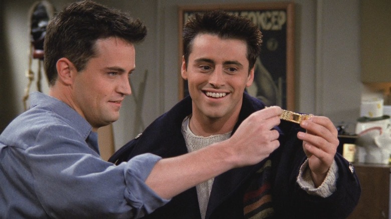 Chandler and Joey hold a bracelet