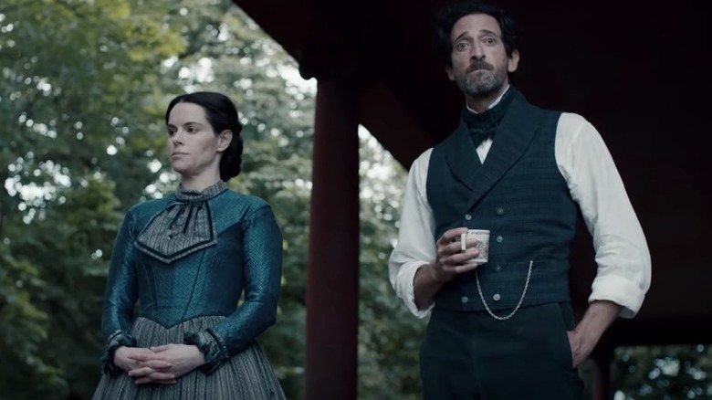 Adrien Brody and Emily Hampshire standing on porch