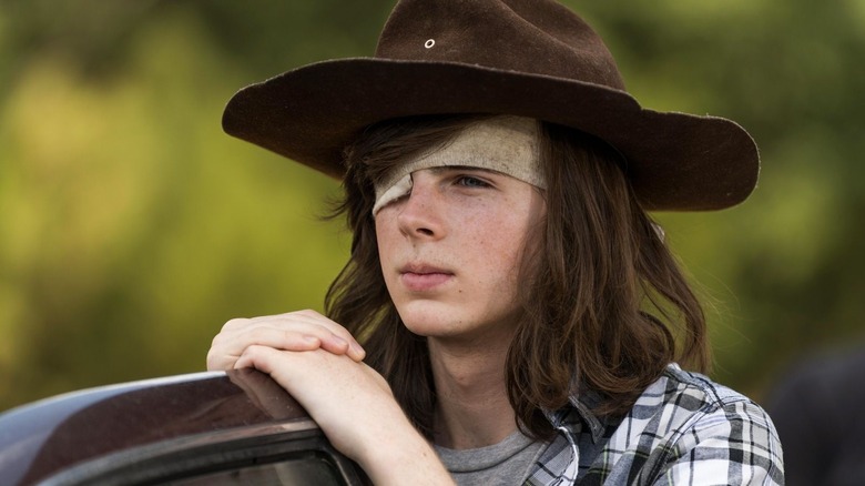 Carl Grimes leaning on a car door in The Walking Dead