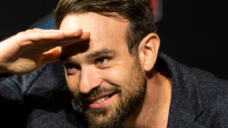 Charlie Cox shielding eyes with hand to get a better look at the audience