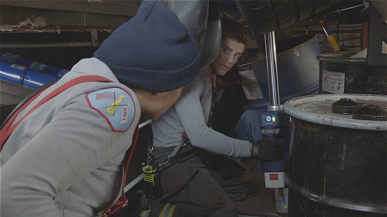 Carver looks at Stella under a car 