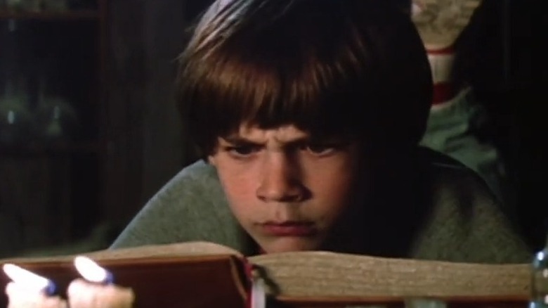 Barret Oliver in The Neverending Story, reading a book in front of candles