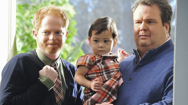 Mitchell and Cameron holding baby Lily in doorway on Modern Family (2009)