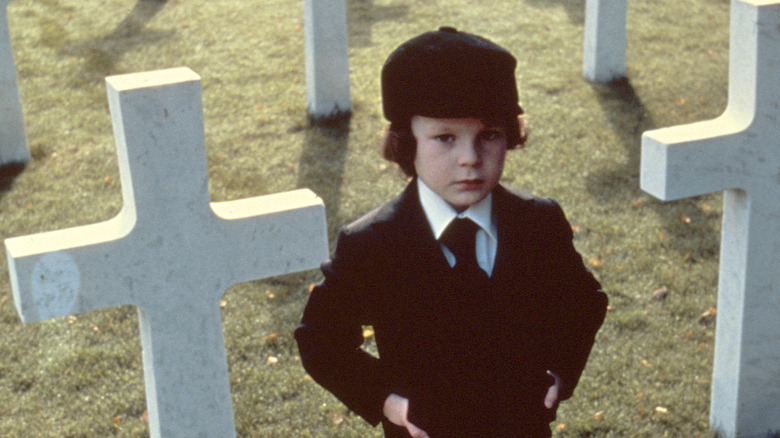 Damien standing in a cemetery in The Omen (1976)