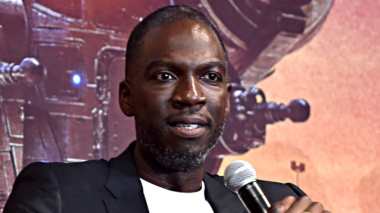 Rick Famuyiwa holding a microphone