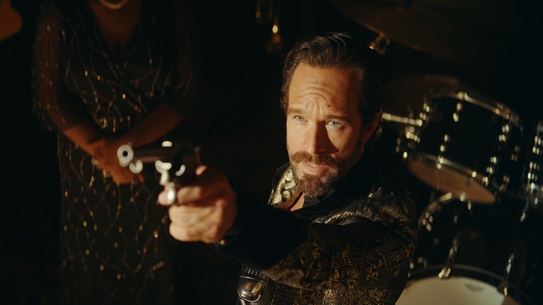 Chris Diamantopoulos pointing a revolver in "Red Notice"