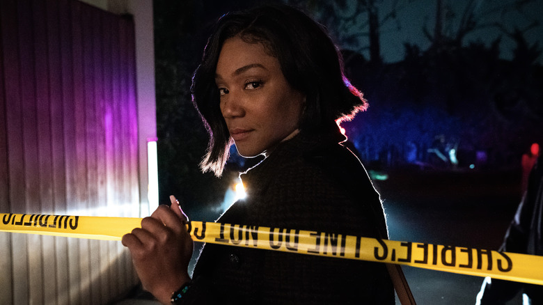 Tiffany Haddish looking at the camera while holding police tape in The Afterparty