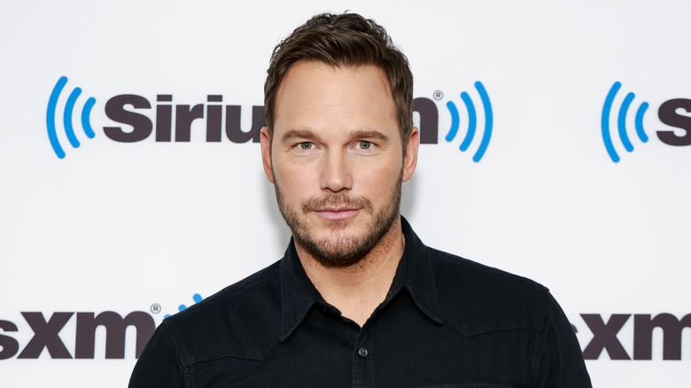 Chris Pratt stands in front of white background with SiriusXM logo