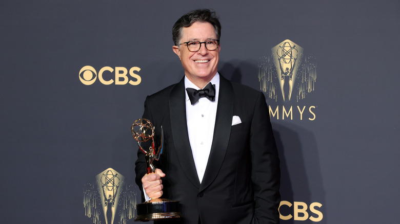 Stephen Colbert smiling wide and holding Emmy