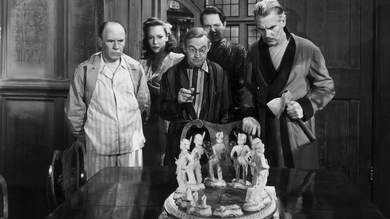 Five guests in pajamas gather around a circle of small statues