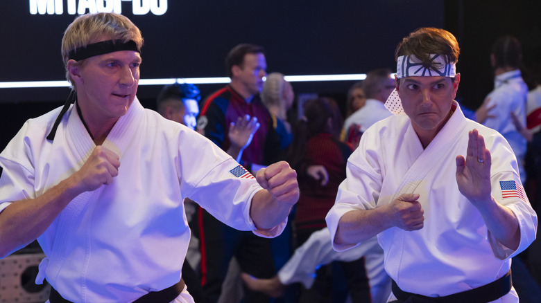 Johnny Lawrence and Daniel LaRusso raise their hands in 