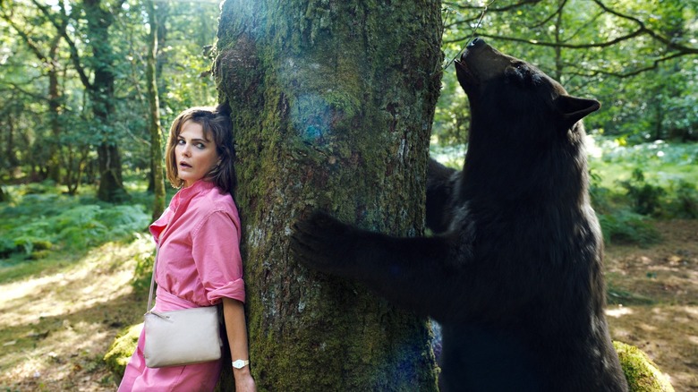 Keri Russell hiding from Cocaine Bear behind tree