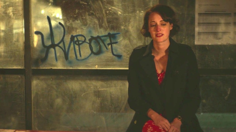 Fleabag sitting alone at a graffitied bus stop