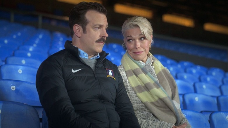 Ted Lasso sitting in the stands with Rebecca Welton