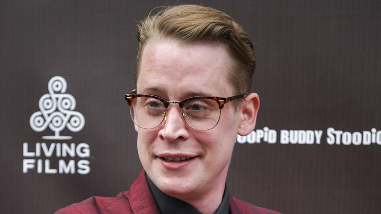 Macaulay Culkin smiling wearing glasses