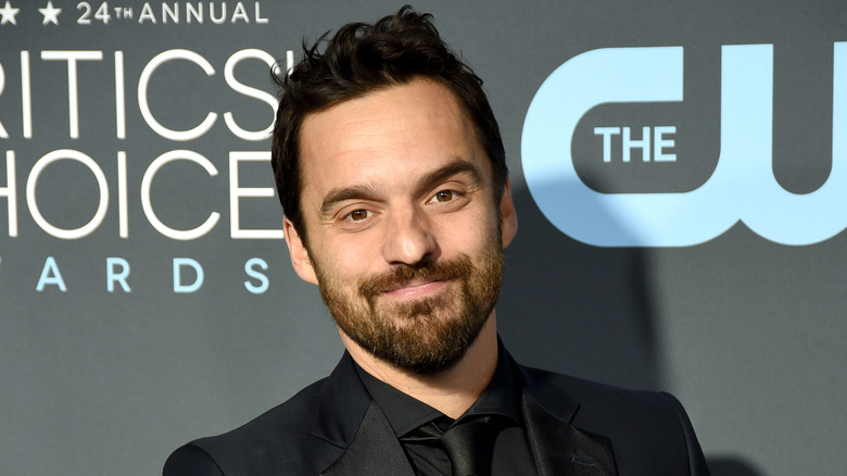 Jake Johnson smiling wearing suit