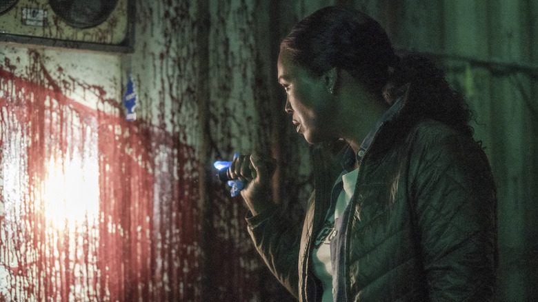 Aisha Tyler as Dr. Tara Lewis shining flashlight on bloodied walls on Criminal Minds: Evolution