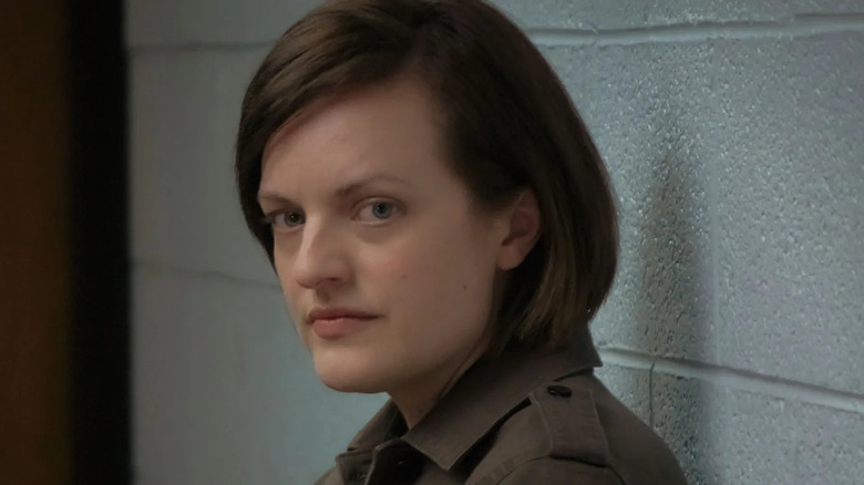 Elisabeth Moss stands against a wall