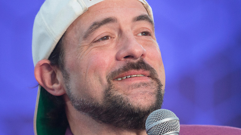 Kevin Smith smiling while holding a microphone