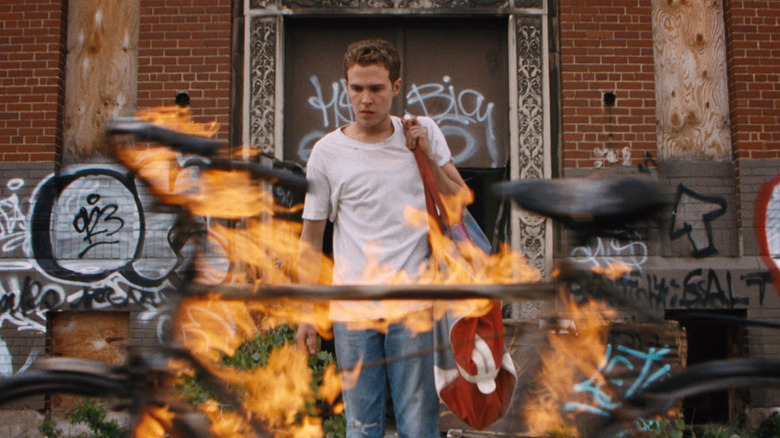 Bones walks amidst flames in "Lost River" (2015)