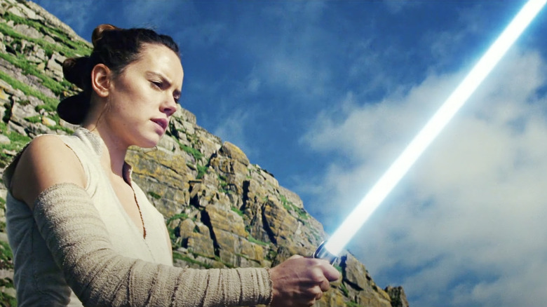 Rey holding blue lightsaber