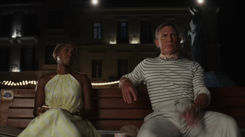 Janelle Monáe and Daniel Craig sitting on bench in Glass Onion