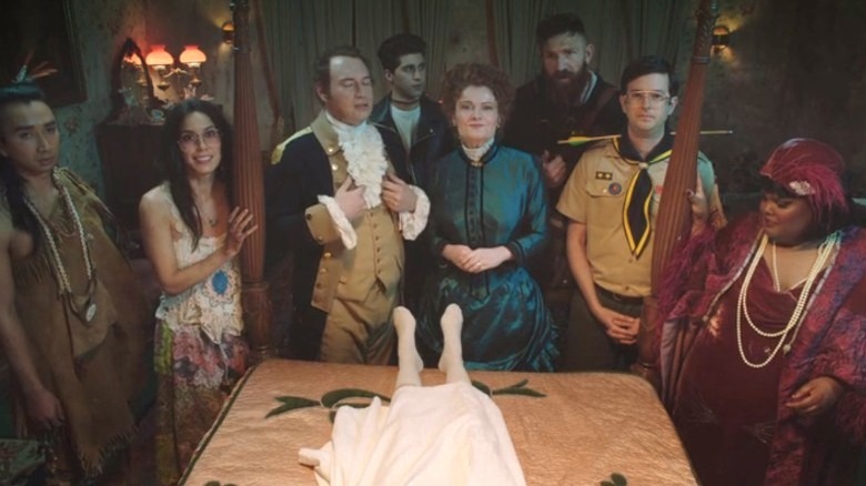 The cast of Ghosts gathered around a bed