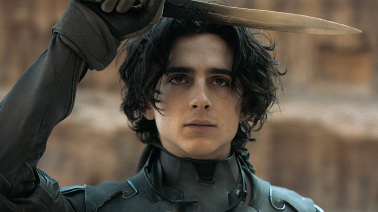 Timothée Chalamet holding a blade above his head in Dune