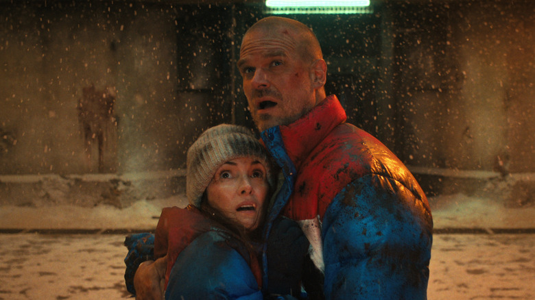 Winona Ryder as Joyce Byers and David Harbour as Jim Hopper hugging as it snows