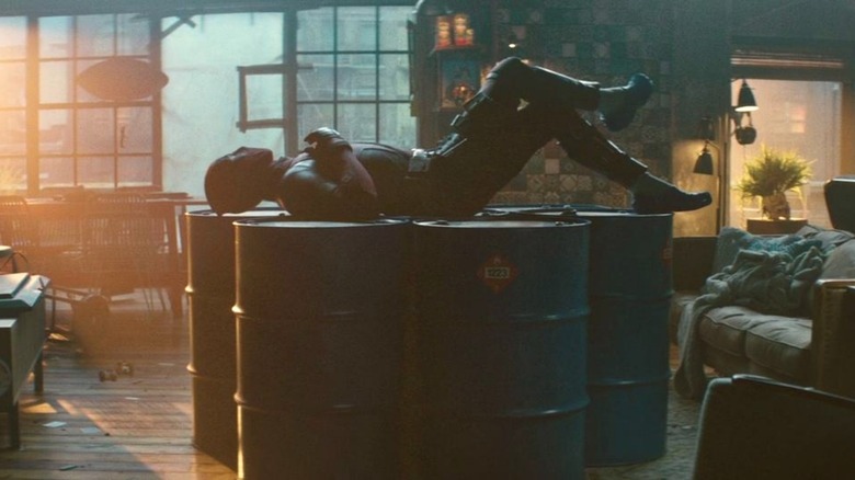 Deadpool lying on fuel barrels