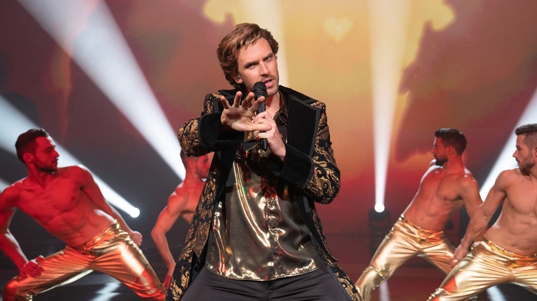 Dan Stevens holds a microphone in Eurovision