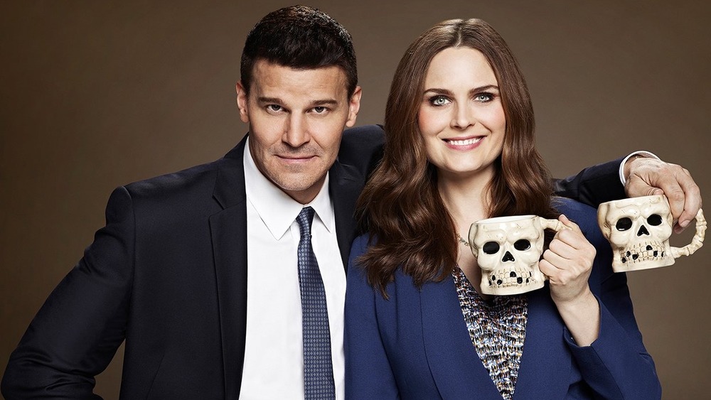 David Boreanaz and Emily Deschanel holding skull mugs