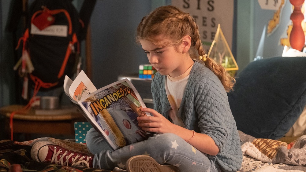 Flora sitting on her bed reading a comic