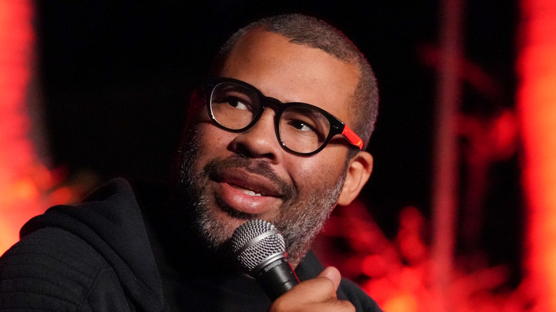 Jordan Peele looking aside with a microphone