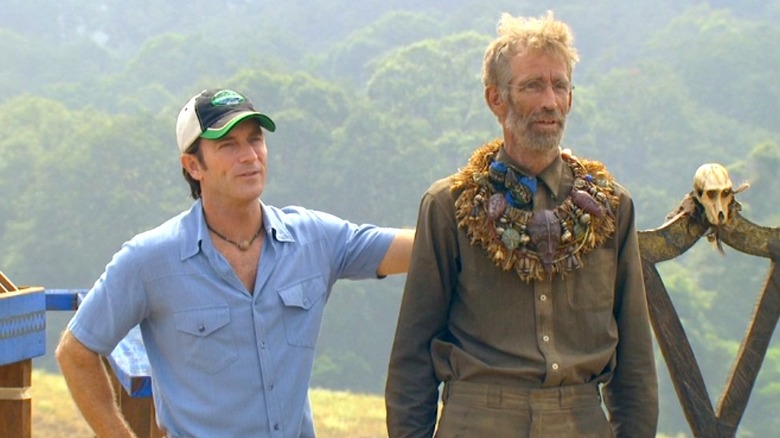 Jeff Probst stands next to contestant Bob Crowley who is wearing the immunity necklace